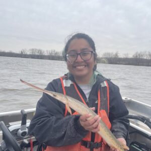 A person smiling holding a fish while on a boat